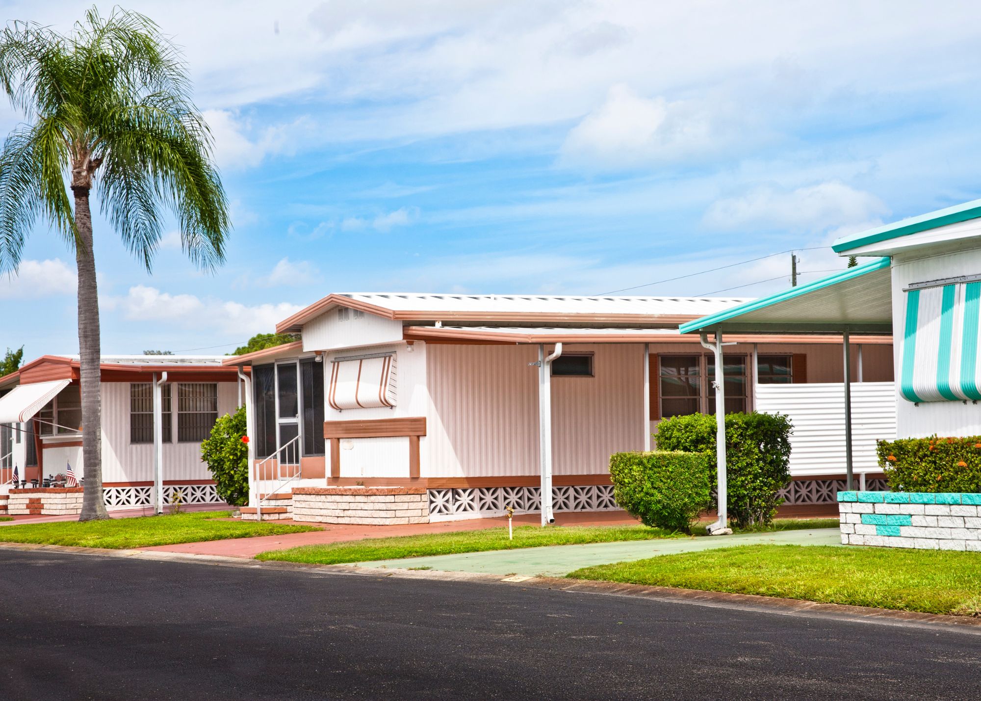 Image of a pink mobile home on a freshly paved street.